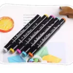 Kit de 5 rotuladores Touch Raven con doble punta de colores negro, amarillo, rosa, celeste y naranja sobre fondo decorado.