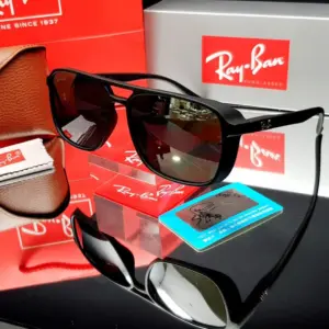 Gafas de sol Ray-Ban cuadradas negras con lentes polarizados, exhibidas sobre una base acrílica junto a su estuche de cuero, paño y tarjeta de prueba.