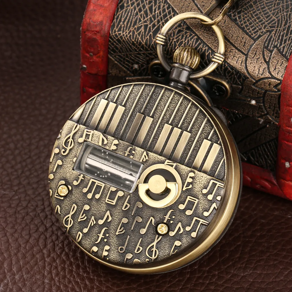 Reloj de bolsillo vintage dorado con motivo de piano y notas musicales sobre superficie de cuero.
