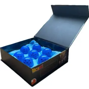 Seis esferas del dragón azules de resina con estrellas negras sobre papel seda azul, contenidas en una caja negra abierta.