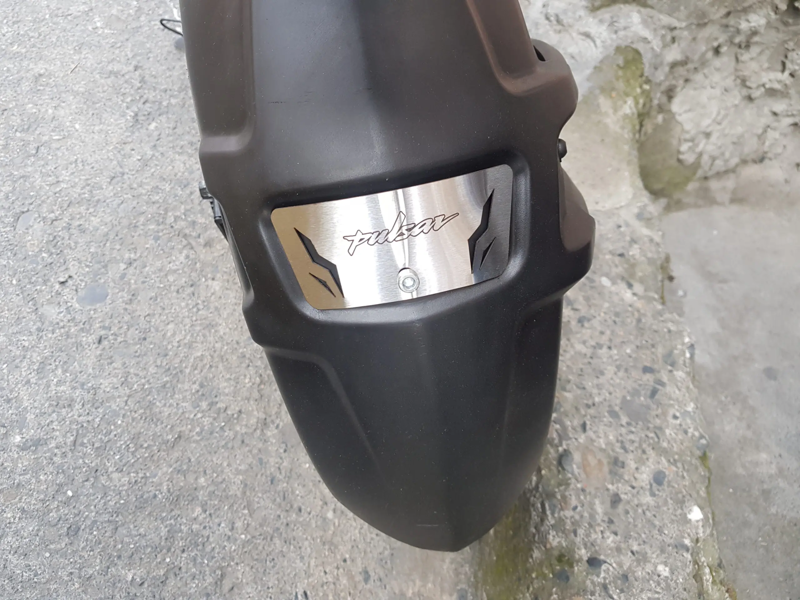 Primer plano de guarda barro negro mate para Pulsar NS 200 con placa de acero inoxidable con el nombre Pulsar grabado.