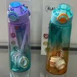 Dos botellas de agua saborizada translúcidas con sorbete y anillos aromáticos en sus cajas, una morada a turquesa y otra turquesa a ámbar.
