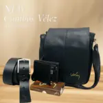 Set de cuero sintético negro con carriel, billetera y cinturón de hebilla plateada marca Vélez sobre una superficie de madera.