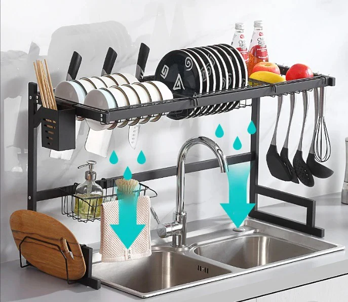 Escurridor de platos metálico negro sobre lavaplatos doble, con platos, tazones, cuchillos y utensilios, optimizando el espacio de secado.