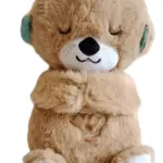 Peluche nutria marrón de pelaje suave con ojos cerrados, vientre con diseño de concha bordada, patas blancas con detalles celestes y función musical.