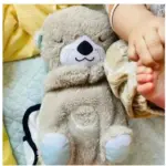Peluche de nutria antiestrés en tono gris claro con textura suave, ojos cerrados y vientre con luz y sonido para descanso de bebés.