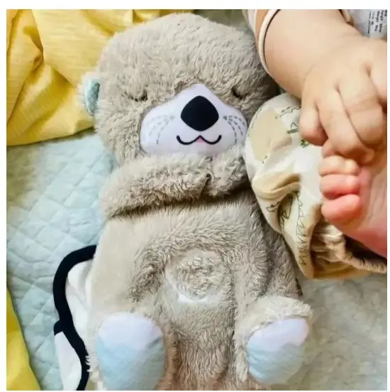 Peluche de nutria antiestrés en tono gris claro con textura suave, ojos cerrados y vientre con luz y sonido para descanso de bebés.