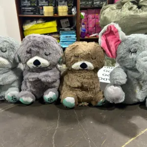Cuatro peluches interactivos musicales para bebé en fila, tres nutrias grises y marrones y un elefante gris con orejas rosadas.
