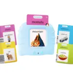 Dispositivo lector electrónico azul claro con ranura superior, mostrando tarjeta rosa de naturaleza sobre "mountain" y cuatro tarjetas didácticas bilingües alrededor.