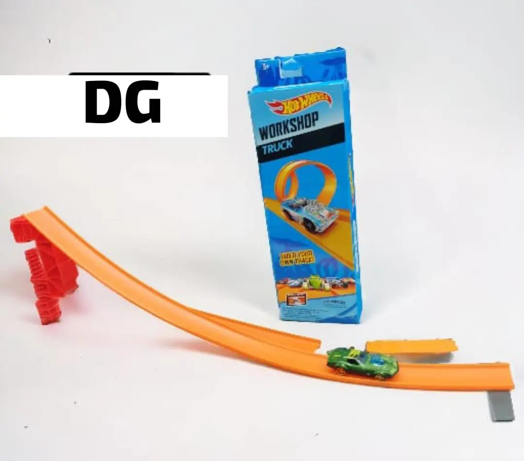 Pista Hot Wheels naranja de acrobacias con rampa roja, carro verde en la vía y caja azul del set Workshop Track.