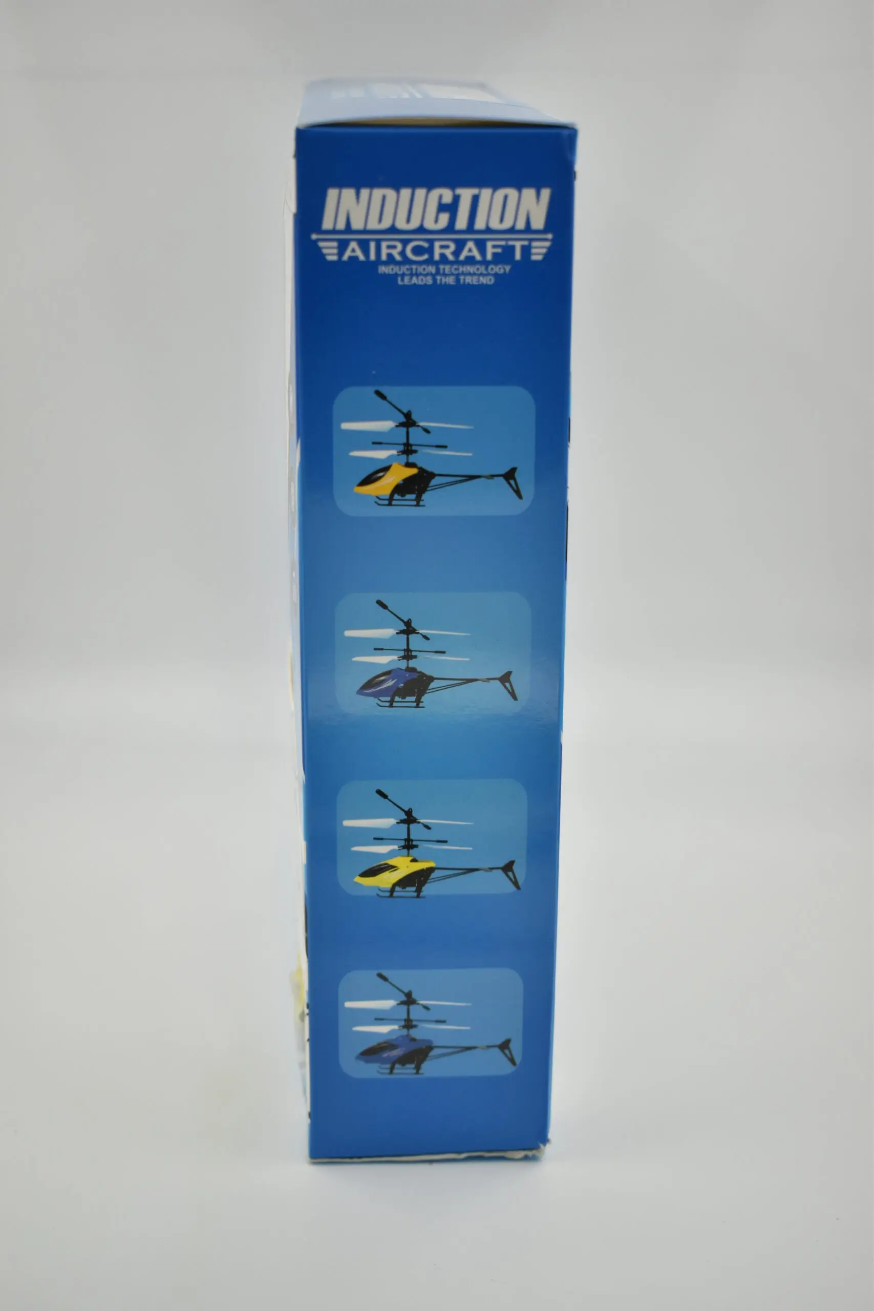 Empaque azul de helicóptero a control remoto Induction Aircraft con modelos ilustrados en colores amarillo y azul.