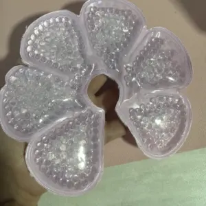 Compresa térmica circular rosa con perlas de gel transparente en forma de flor, ideal para terapia de frío y calor.