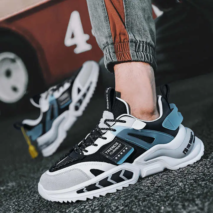 Zapatillas urbanas para hombre en negro, blanco y azul con suela gruesa ondulada y detalles texturizados, vistas en ángulo sobre asfalto.