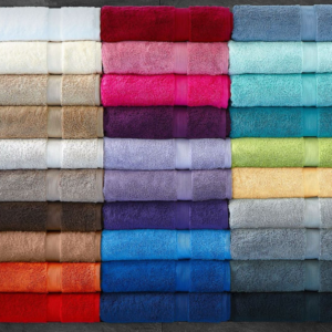 Variedad de toallas de baño de algodón dobladas en columnas, mostrando múltiples colores desde tonos neutros hasta vibrantes.