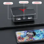 Estuche de carga negro con indicador LED digital y un audífono inalámbrico plateado sobre un teléfono inteligente.