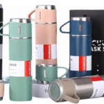 Set de termos de acero inoxidable mate en negro, verde, rosa, azul y plata, con tazas pequeñas y bolsa negra.