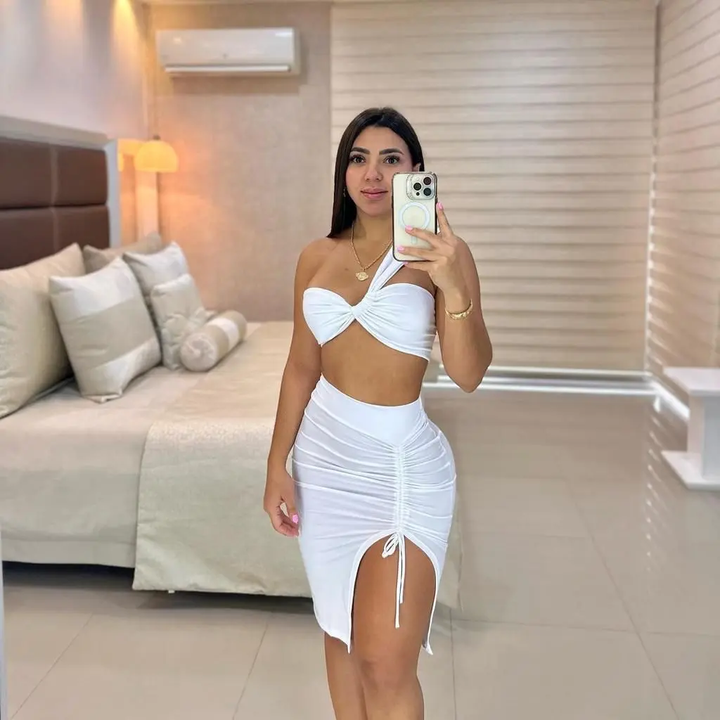 Conjunto blanco de dos piezas con top bandeau cruzado y falda ajustada de tiro alto con fruncido central y abertura lateral con lazo.