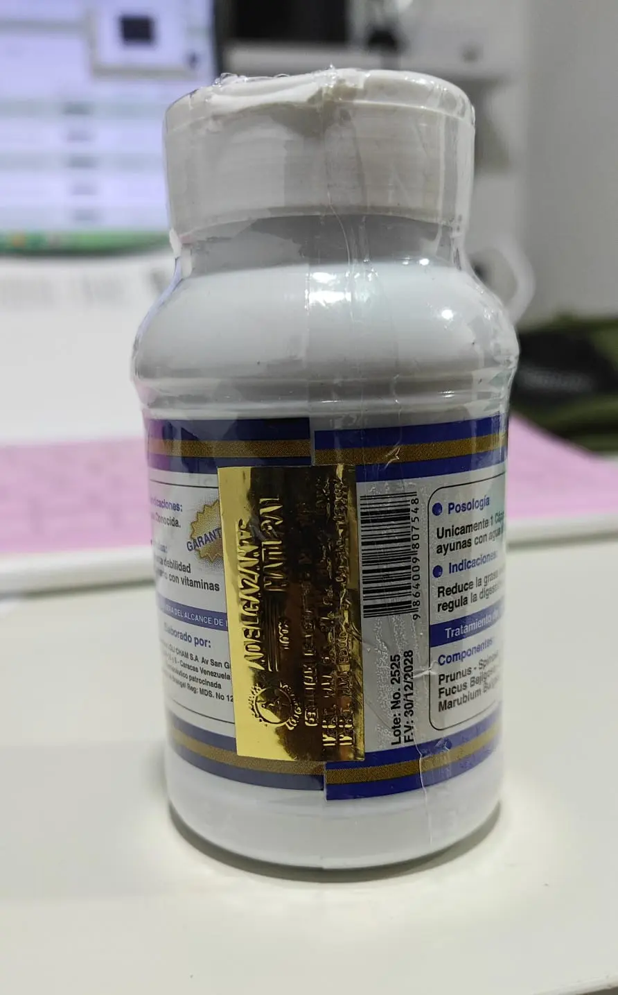 Frasco blanco de cápsulas adelgazantes Loli Cham con etiqueta azul y dorada, detalle en foil dorado y empaque sellado en plástico.