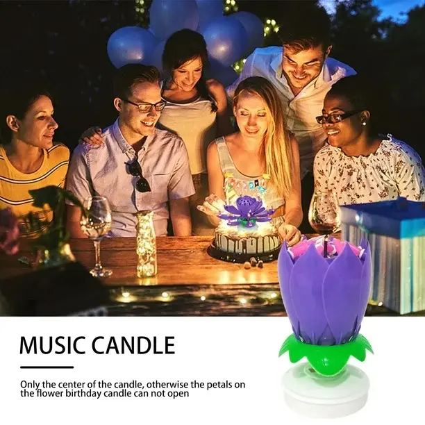 Vela musical morada en forma de flor para cumpleaños, junto a grupo celebrando alrededor de una tarta con otra vela encendida sobre mesa de madera.