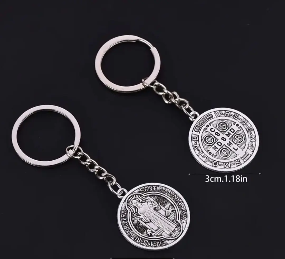Dos llaveros metálicos plateados con la medalla de San Benito de 3 cm, que muestran ambos lados con detalles grabados y argolla de acero.