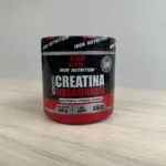Envase cilíndrico negro con detalles rojos de creatina monohidrato en polvo Iron Nutrition, presentación de 150 gramos sobre una superficie de madera.