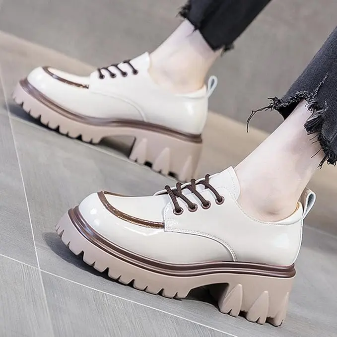 Zapatos de plataforma Cairluxe en charol marfil con suela gruesa track marrón, cordones oscuros y costuras decorativas.