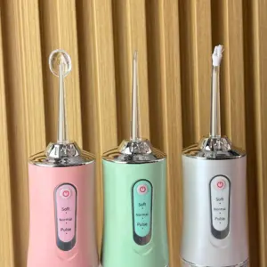 Tres irrigadores bucales portátiles recargables sobre fondo estriado de madera, en colores rosado, verde claro y gris, con boquillas especializadas diferentes.