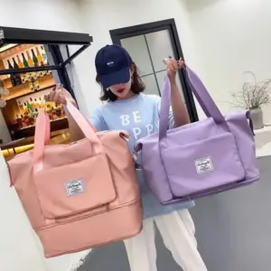 Mujer con gorra sostiene dos bolsos de viaje expandibles e impermeables de nailon, uno en color rosado y otro en tono lila.
