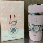 Perfume Lattafa Yara rosa de 100 ml con atomizador y su caja decorada en tonos claros sobre superficie lisa.