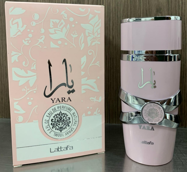 Perfume Lattafa Yara rosa de 100 ml con atomizador y su caja decorada en tonos claros sobre superficie lisa.