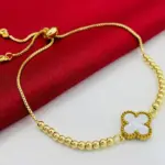 Pulsera dorada con cuentas tipo balín y dije central de trébol blanco, con cierre ajustable de cadena fina.
