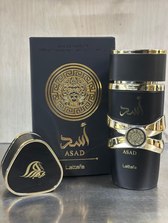 Perfume Lattafa Asad Eau de Parfum de 100 ml con frasco negro mate, detalles dorados, caja y tapa triangular con el logotipo.