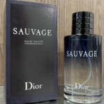 Perfume Dior Sauvage Eau de Toilette de 100 ml con frasco de vidrio degradado azul y tapa negra junto a su caja azul oscuro sobre madera.