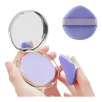 Polvo matificante compacto color lavanda en estuche transparente con espejo y esponja aplicadora morada en forma de gota.