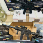 Pistola de hidrogel Arp9 negra con mira holográfica, empuñadura vertical y lanzagranadas, presentada sobre su caja de empaque.
