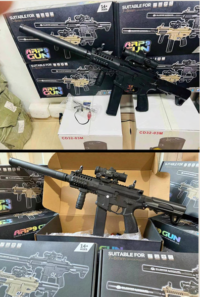 Pistola de hidrogel Arp9 negra con mira holográfica, empuñadura vertical y lanzagranadas, presentada sobre su caja de empaque.