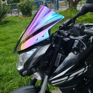 Cúpula tornasol multicolor instalada en moto Bajaj Pulsar NS negra, vista en ángulo frontal resaltando su acabado iridiscente.