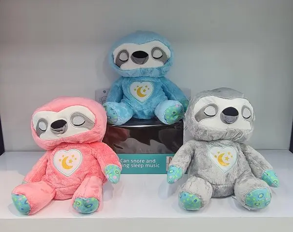 Tres peluches de perezoso interactivos antiestrés en colores rosado, azul y gris con corazón iluminado con luna y estrellas en el pecho.
