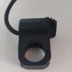 Interruptor de manillar negro con abrazadera circular ajustable, cable de conexión y botón de encendido con protector de goma.