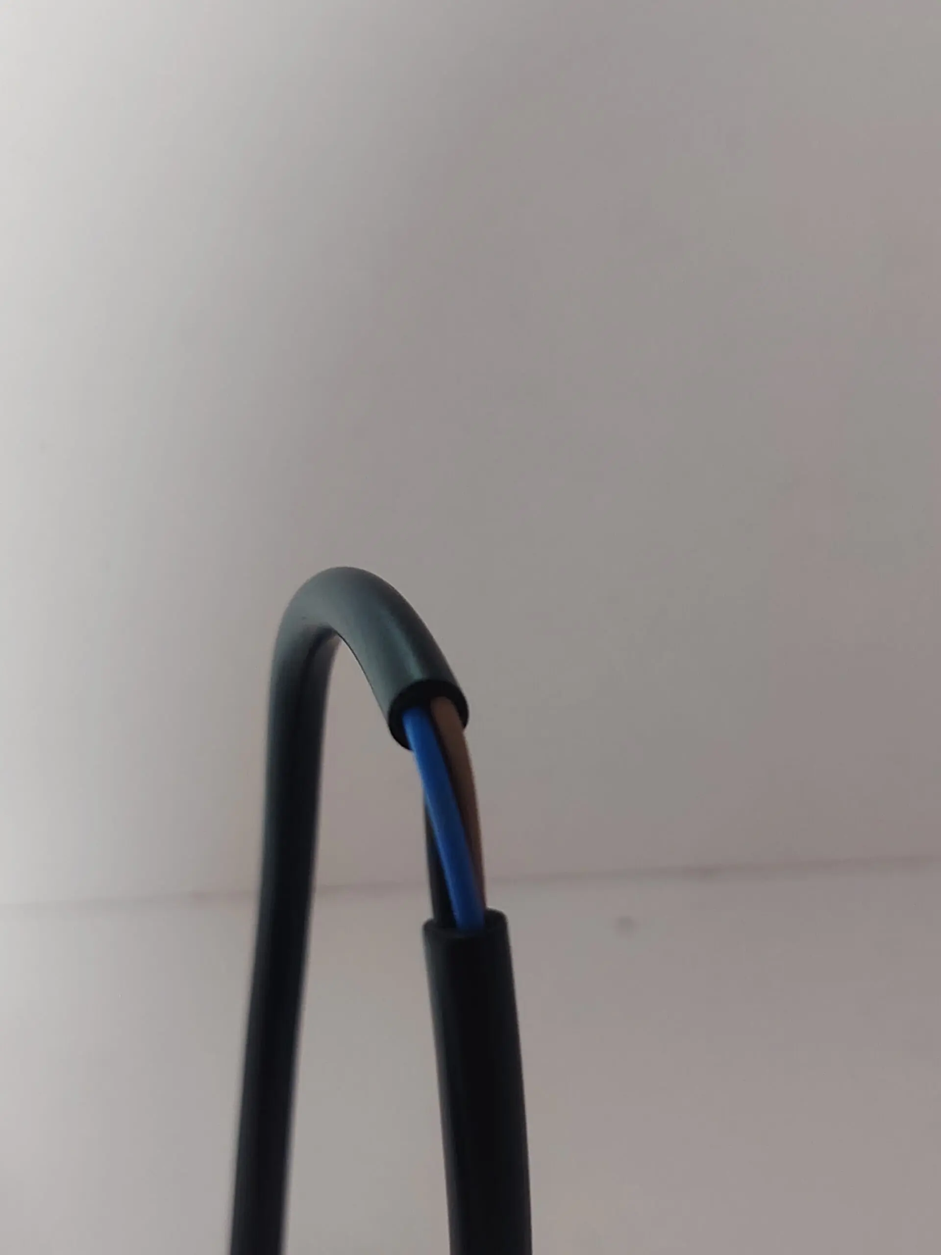 Interruptor de manillar para moto con cable negro de salida que expone cables internos azul y marrón.
