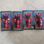 Cuatro guantes rojos lanzadores de agua para niños y cosplay de Spiderman en empaques originales sobre piso de cerámica.