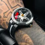 Reloj deportivo negro de goma para caballero con esfera inspirada en rin de auto, detalles en rojo y logotipo de Ferrari.