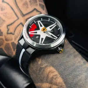 Reloj deportivo negro de goma para caballero con esfera inspirada en rin de auto, detalles en rojo y logotipo de Ferrari.