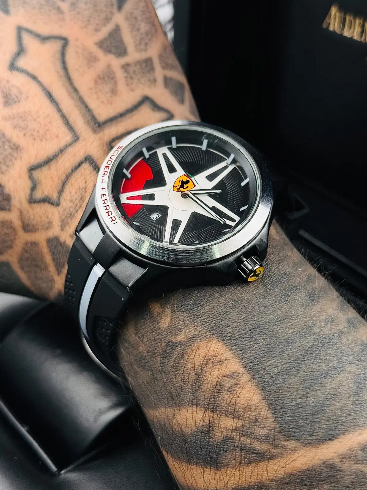 Reloj deportivo negro de goma para caballero con esfera inspirada en rin de auto, detalles en rojo y logotipo de Ferrari.