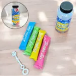 Set de líquido para burbujas con cuatro sobres coloridos en azul, verde, amarillo y rosa, varita plástica y botella plástica transparente.