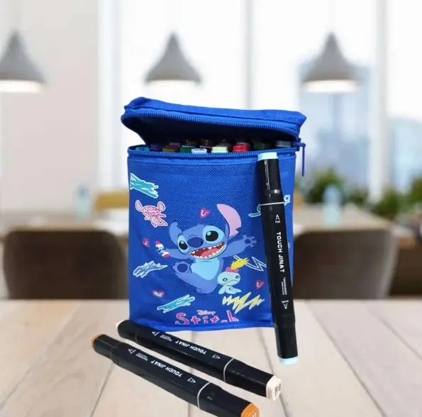 Estuche organizador azul textil con diseño de Stitch y marcadores duales incluidos, sobre mesa de madera en interior.