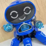 Robot juguete interactivo azul de seis patas con pantalla LED de ojos luminosos y manos translúcidas iluminadas.