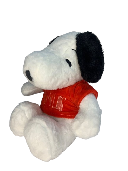 Peluche de Snoopy blanco con orejas negras y camiseta roja con la palabra Smiles, en posición sentada de perfil y textura suave.