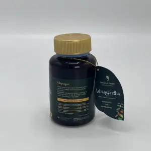 Frasco oscuro de Ashwagandha orgánica con tapa dorada y etiqueta colgante en forma de hoja con detalles botánicos sobre fondo neutro.