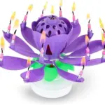 Vela de cumpleaños en forma de flor de loto color morado abierto con pétalos extendidos y velas encendidas en cada punta.